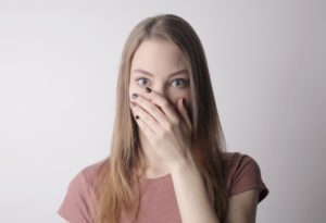 young amazed woman in casual wear covering mouth while