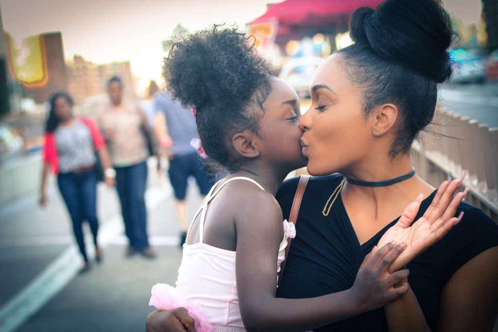 black woman and child kissing on cheek calming tantrum co-regulating